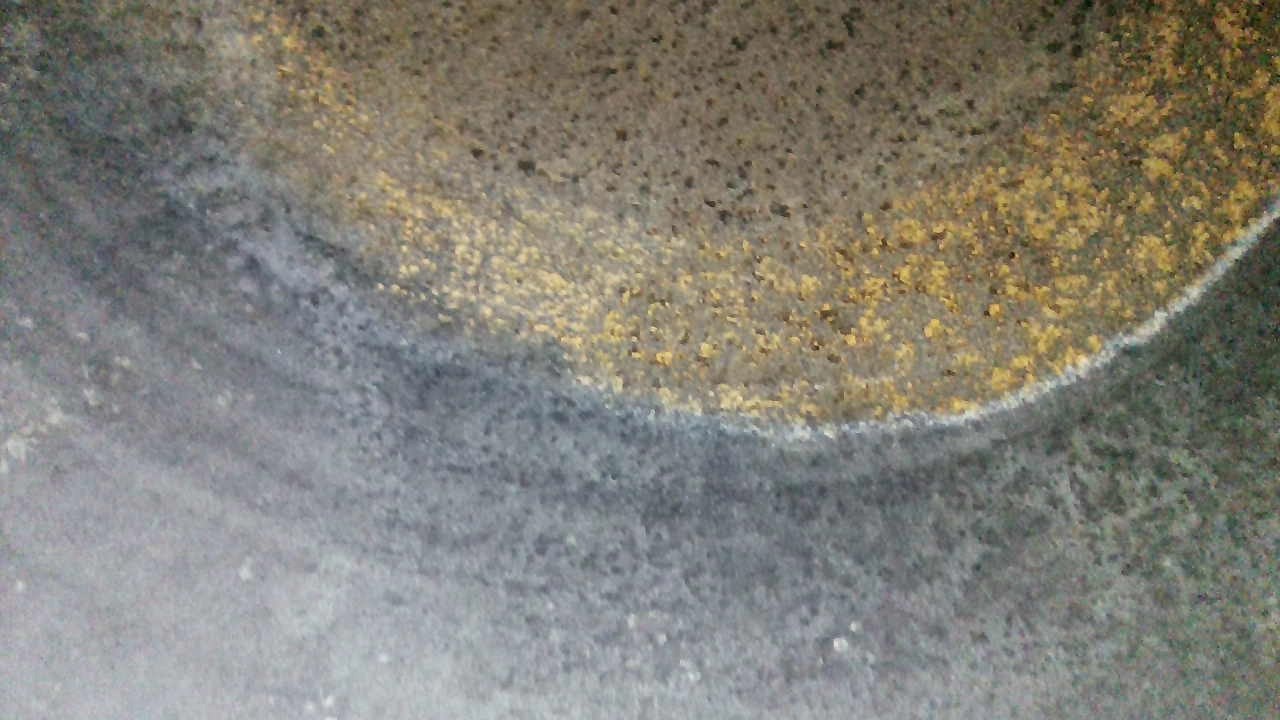 Blick mit der Kamera ins Innere einer Stahlflasche, der Boden ist mit rostbraunen Punkten übersät.