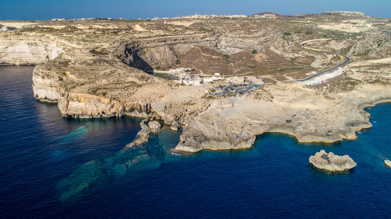 Luftaufnahme der Steilküste von Gozo mit türkisem Flachwasser und Tauchplatz vor der Felsküste